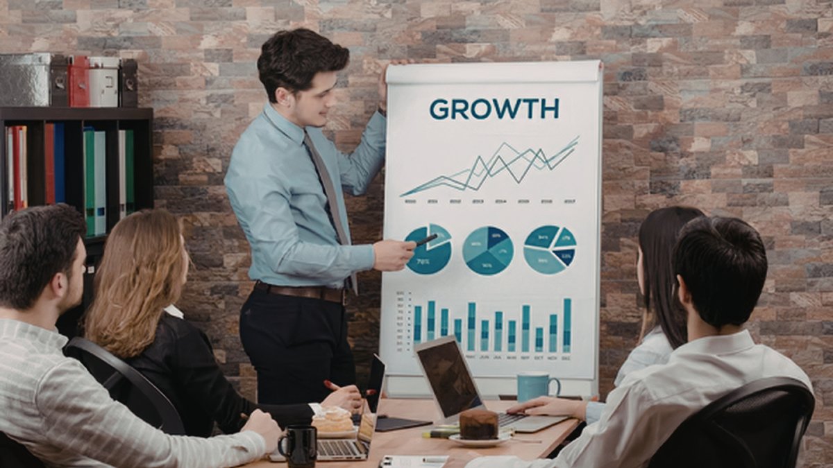 Man presenting a growth chart to coworkers in a conference room.